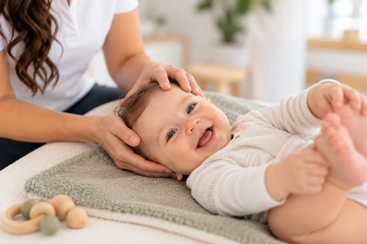 Sanfte osteopathische Behandlung eines lachenden Babys am Köpfchen